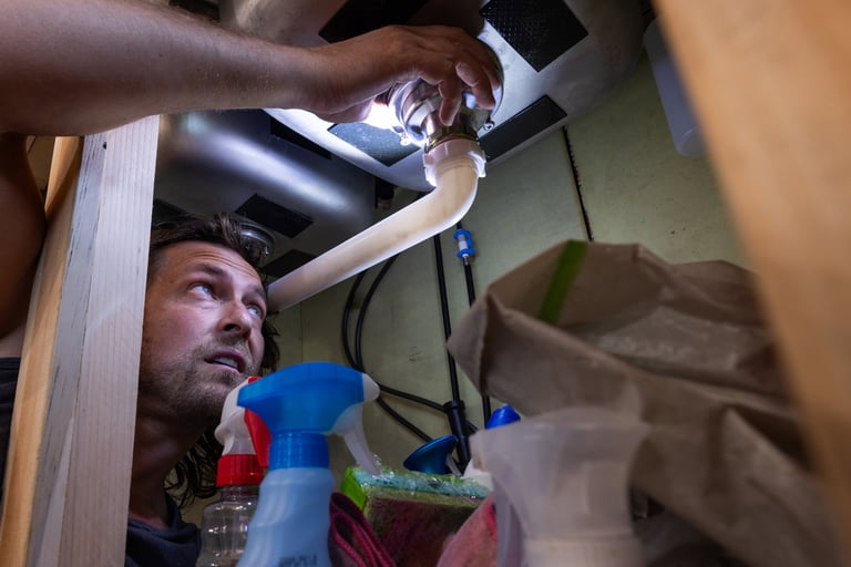 Plumber repairing plumbing under kitchen sink